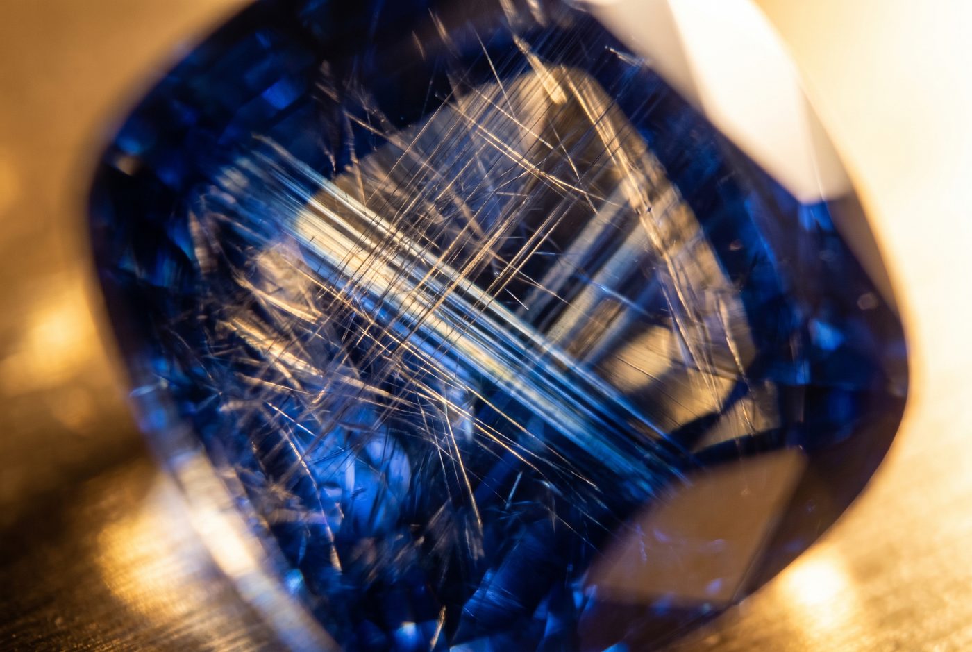 Blue sapphire under gemmological microscope showing fine rutile silk and colour zoning