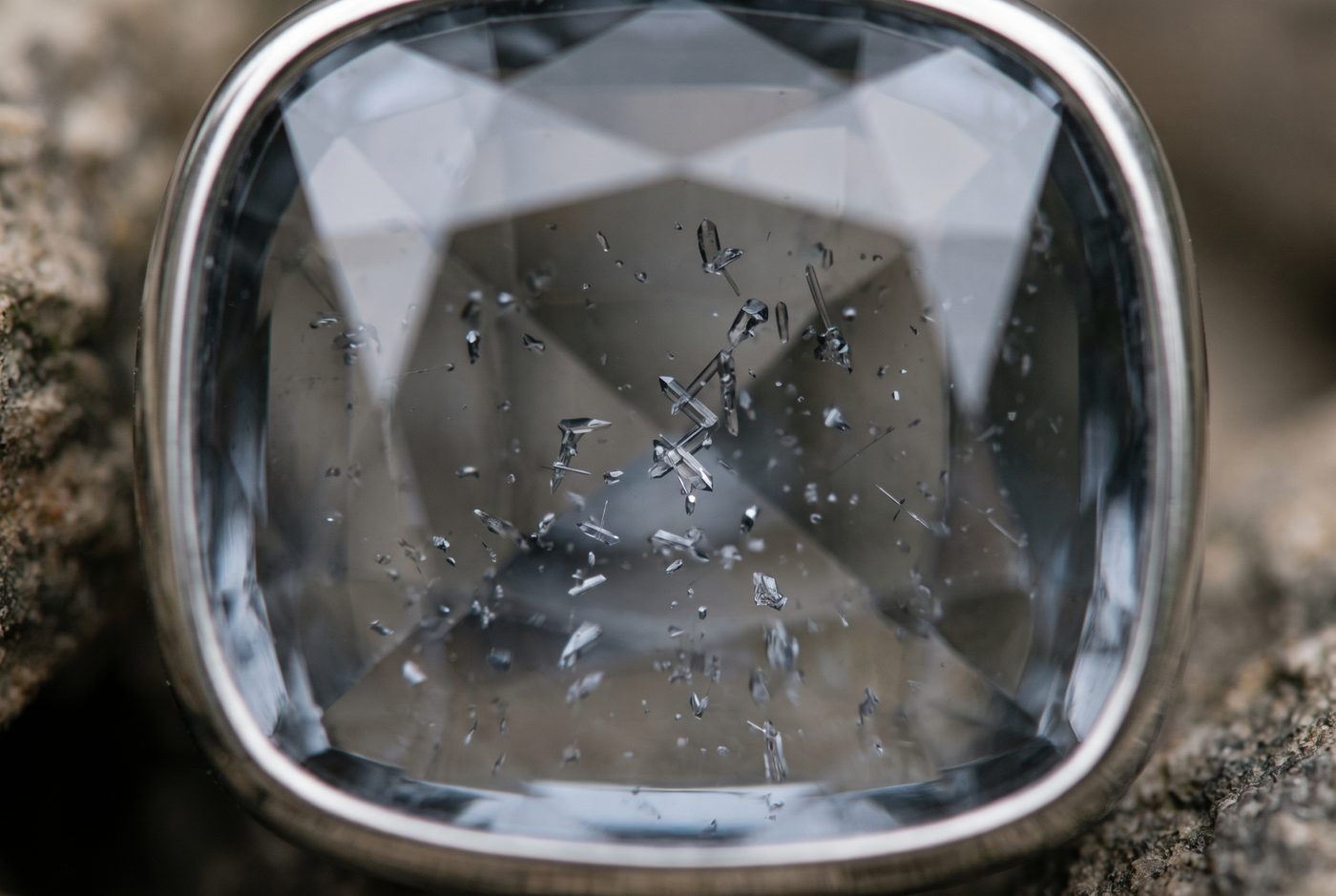 Macro loupe view of tiny natural crystal inclusions inside a transparent grey spinel